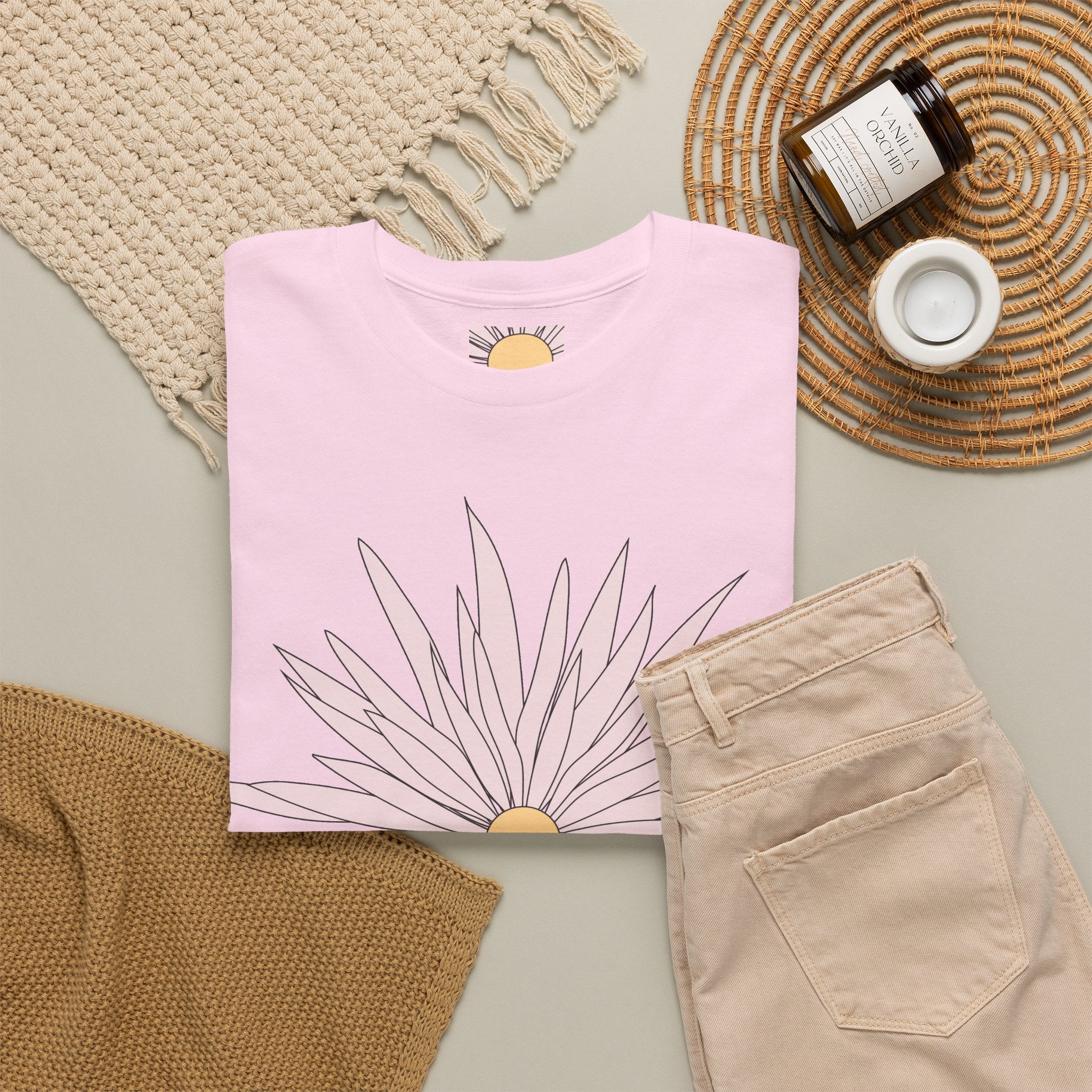 Light pink graphic tee laid flat with large daisy flower print and small daisy sleeve details.