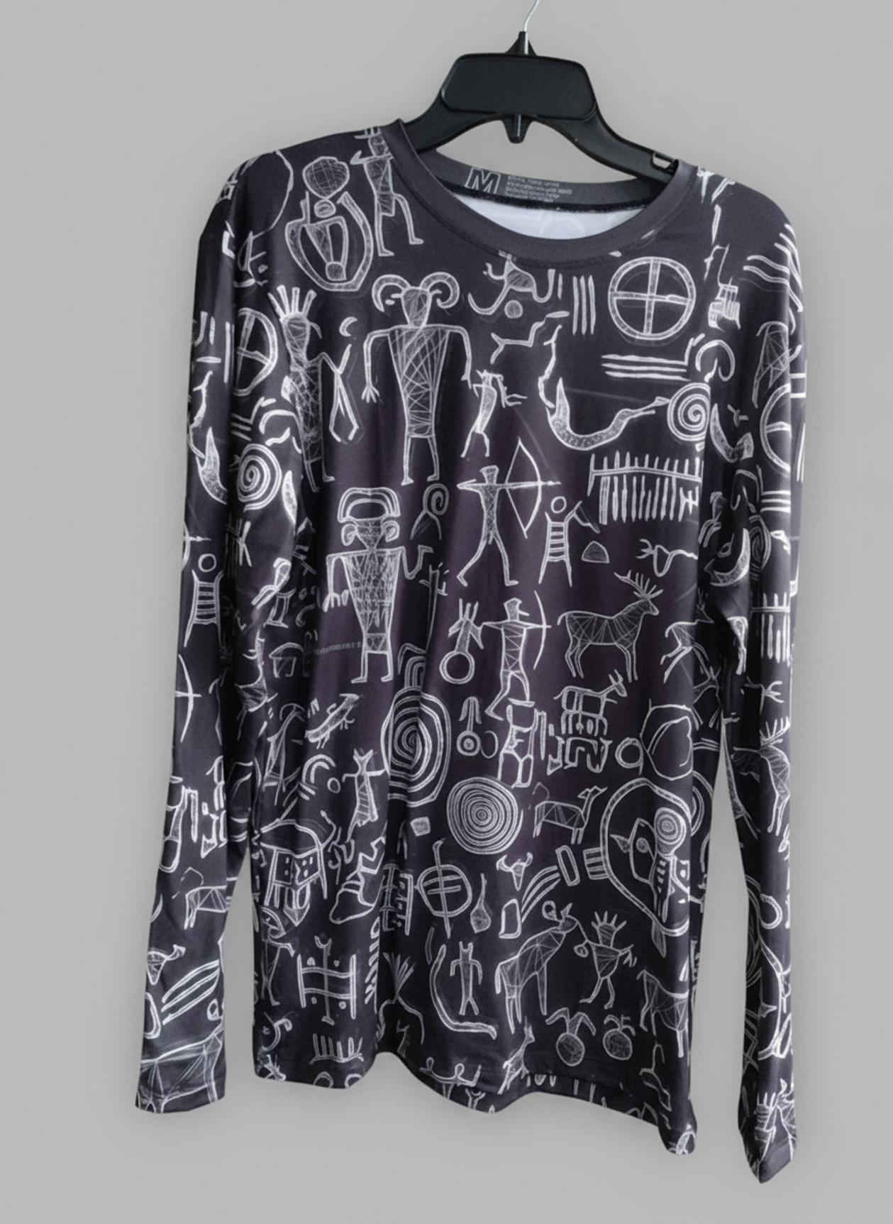 Black long-sleeve shirt hanging with all-over white petroglyph-style line art